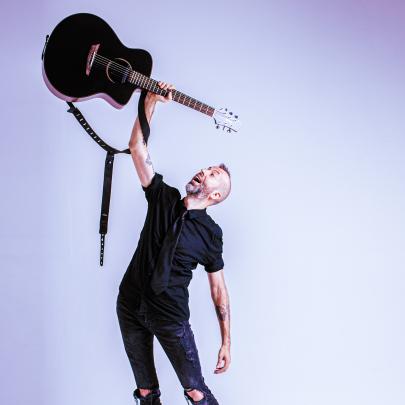Jon Gomm holding guitar above head